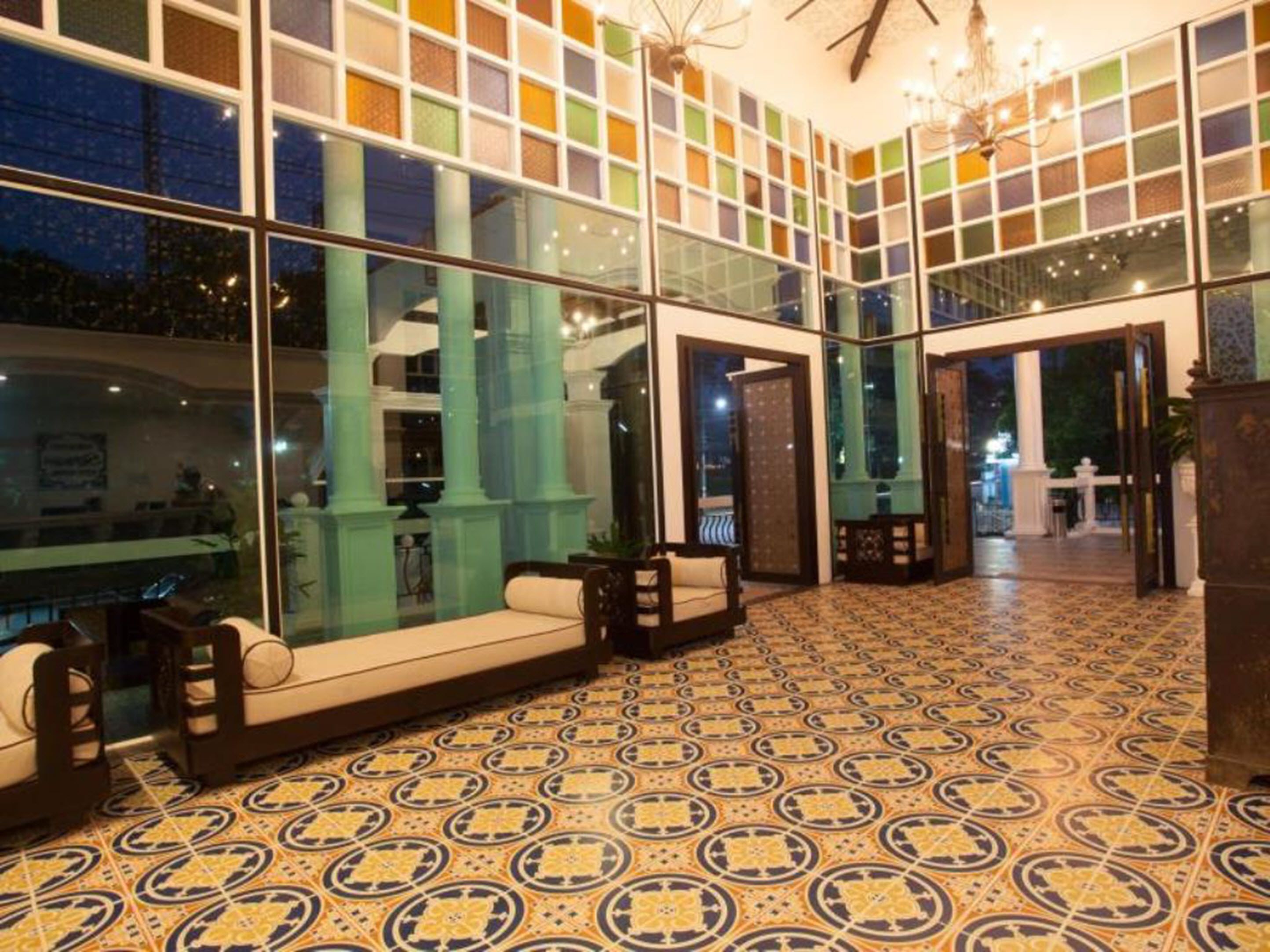 A lobby with large windows, patterned floor tiles, and a seating area with sofas and a table.