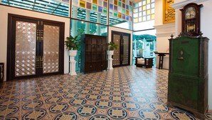 A spacious lobby with patterned floor tiles, a large glass wall, and a green cabinet. - Grand Supicha City Hotel (Phuket)