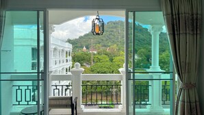 A balcony with a view of a traditional building and lush greenery. - Grand Supicha City Hotel (Phuket)