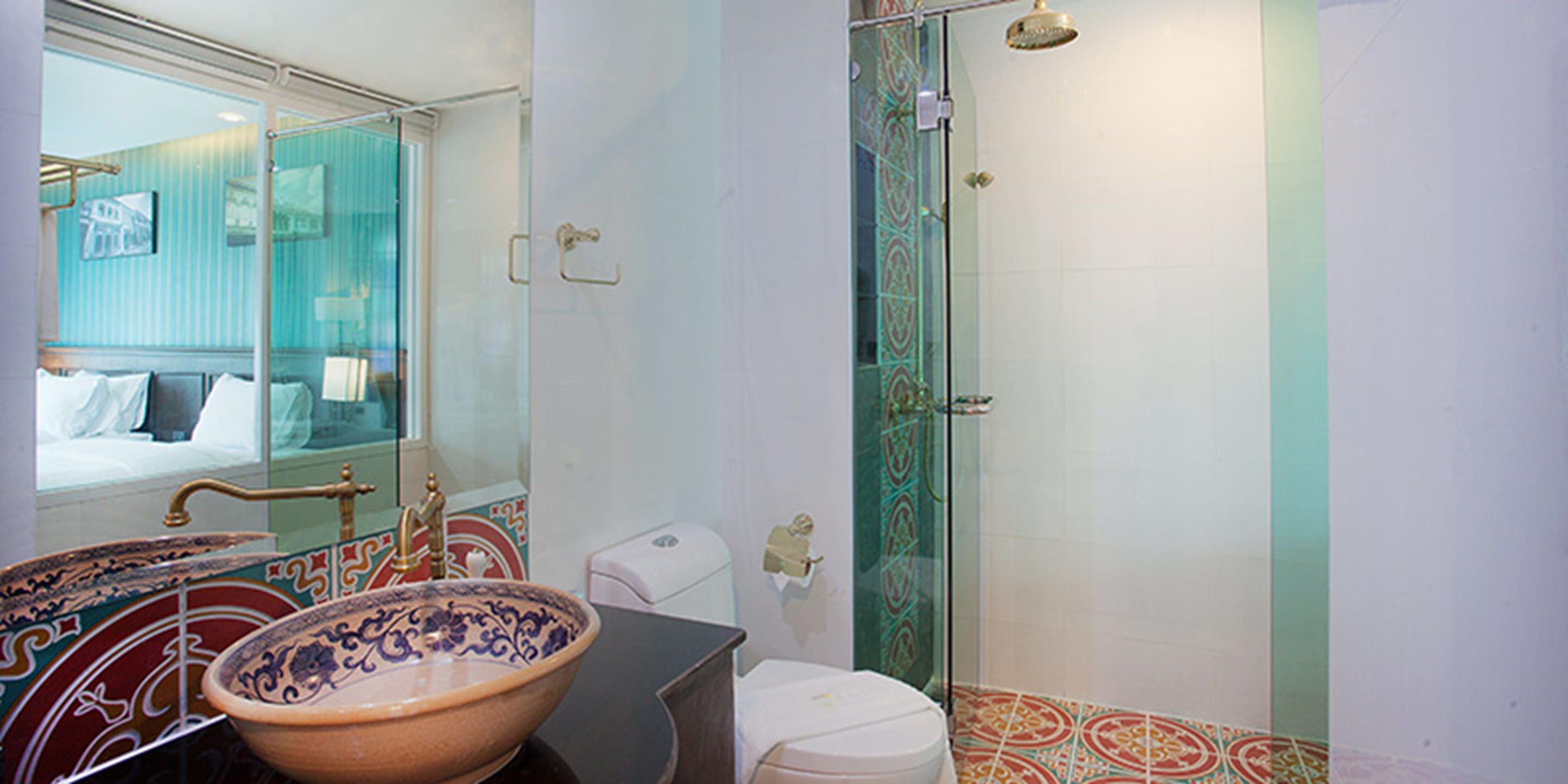 A bathroom with a large decorative bowl sink, a toilet, and a glass-enclosed shower.