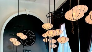 A cafe interior with a black and white color scheme, a cash register, a display case with pastries, and a table with chairs. - Grand Supicha City Hotel (Phuket)
