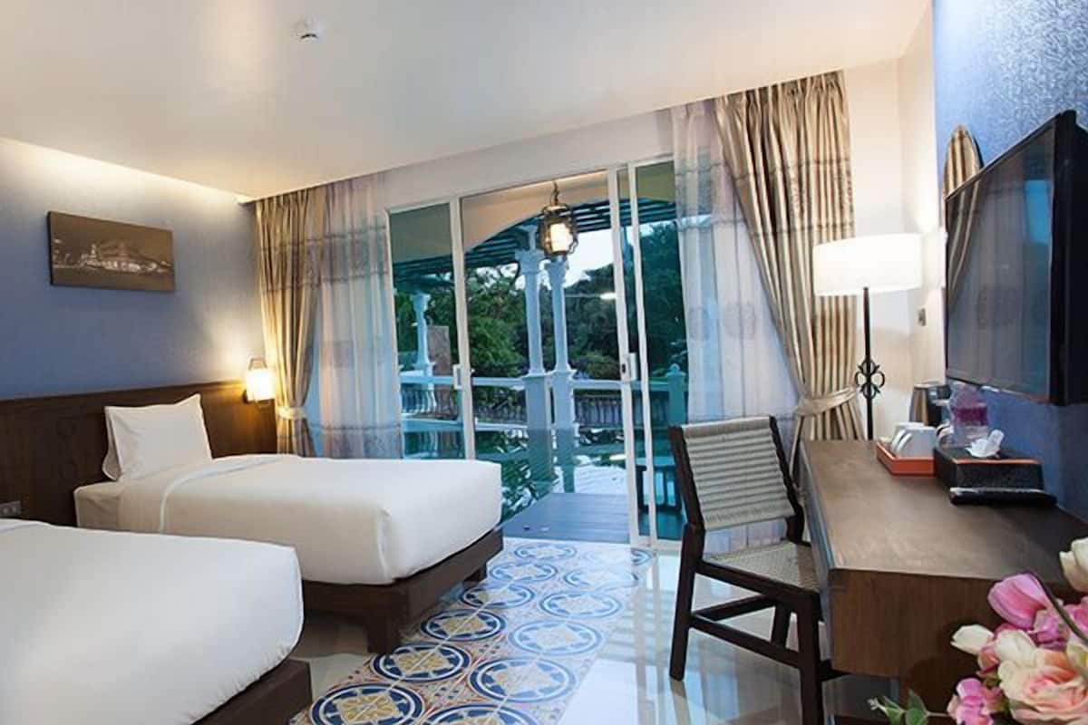 A hotel room with two beds, a desk, a chair, a TV, and a balcony with a view.