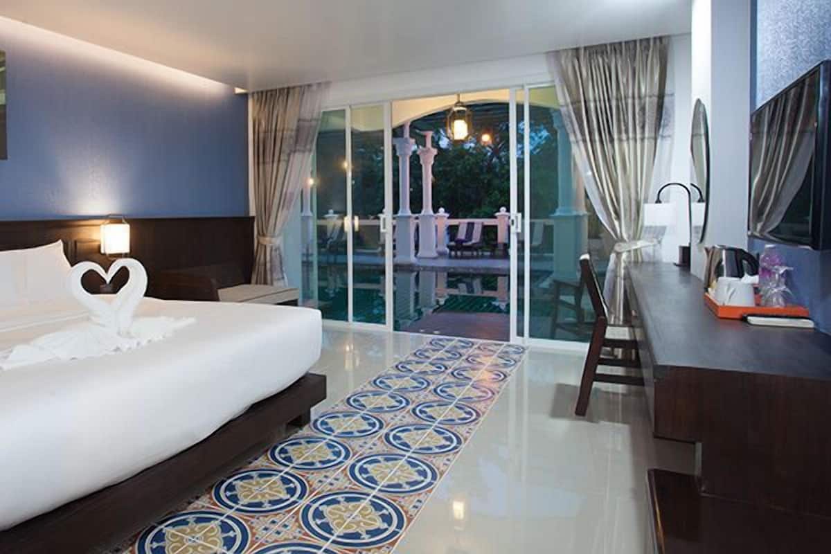 A hotel room with a large bed, a desk, and a view of the outside.
