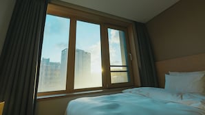 Una habitación de hotel con un ventanal grande, una cama y vistas a un paisaje urbano.