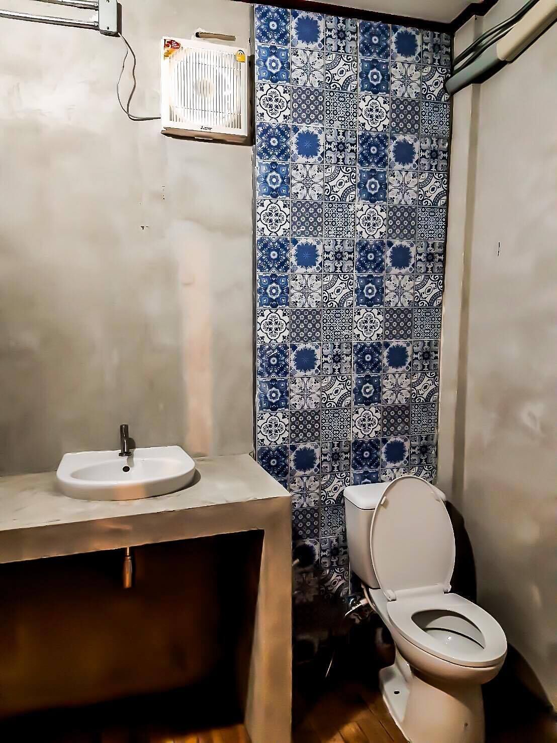 A bathroom with a white sink, toilet, and patterned tiles.
