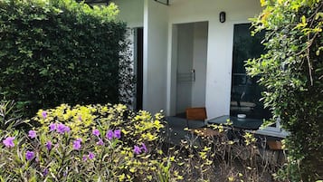 Un edificio moderno con puerta de cristal y un pequeño espacio de descanso con mesa y silla.