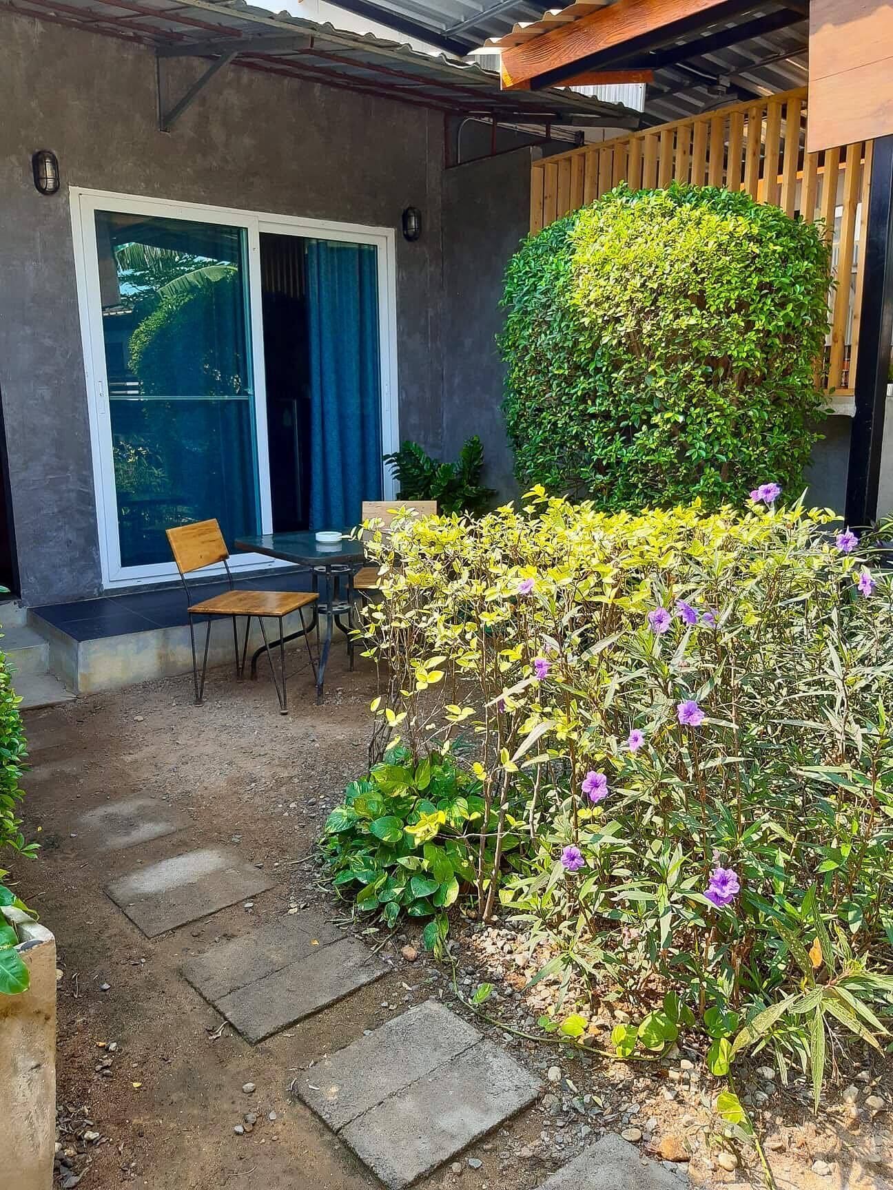 A patio area with a table and chairs, a wooden fence, and a variety of plants.