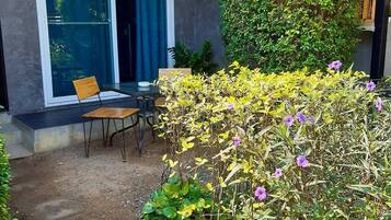 A patio area with a table and chairs, a wooden fence, and a variety of plants.