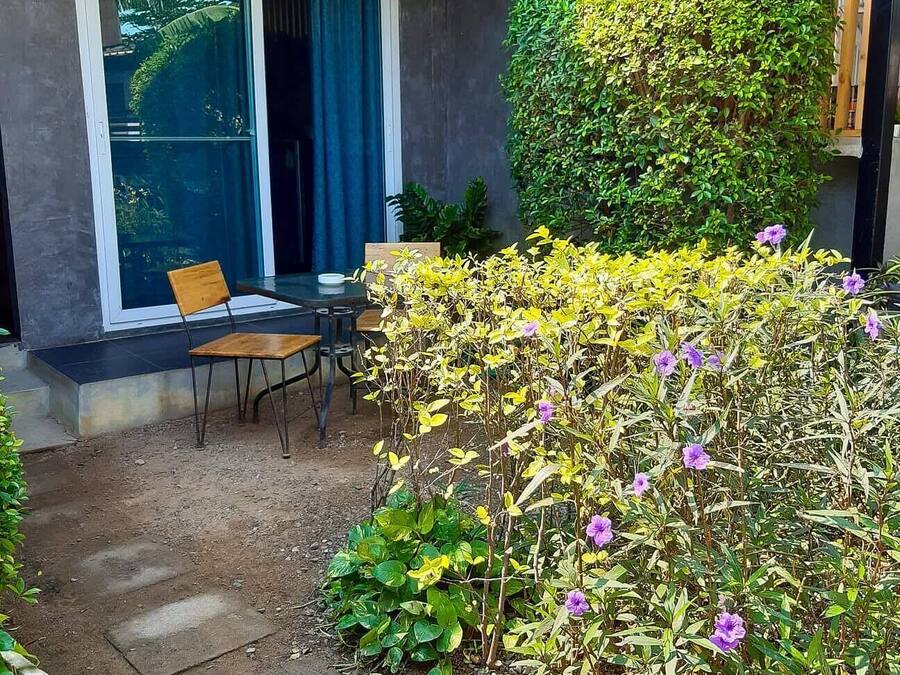 A patio area with a table and chairs, a wooden fence, and a variety of plants.