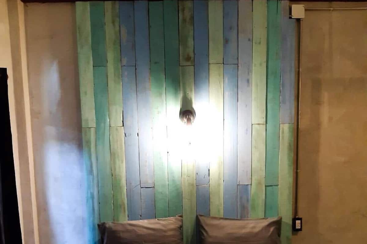 A bedroom with a bed, pillows, and a wall with vertical wooden panels.