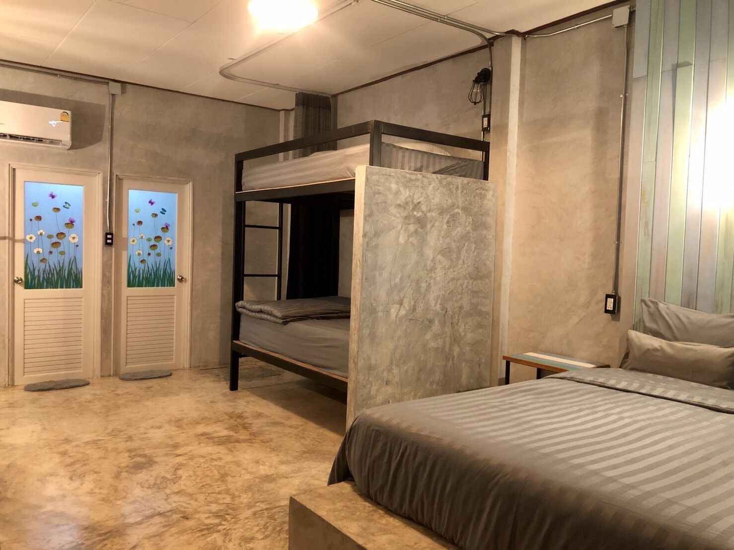 A room with bunk beds, a large bed, and a door with a floral decal.