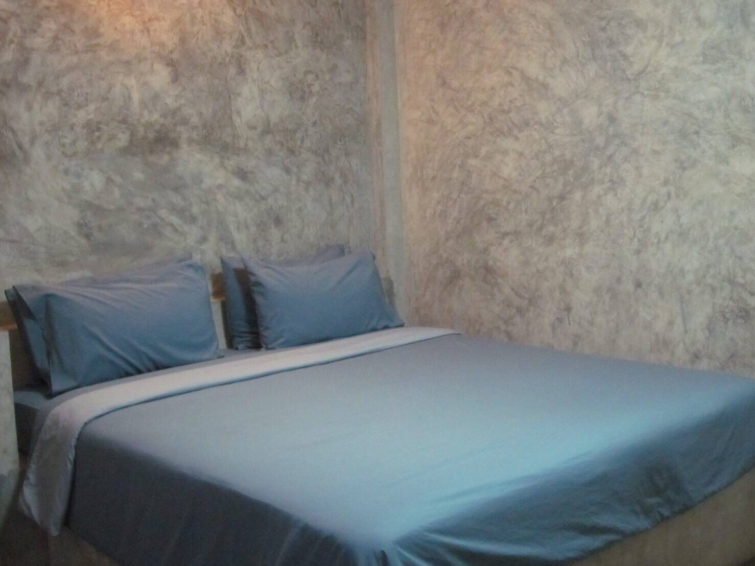 Une chambre à coucher avec un lit, des oreillers et un mur à texture.