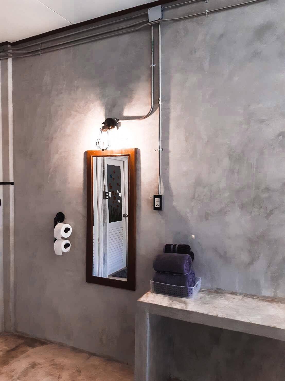 Un baño con un espejo grande, un perchero para toallas y un dispensador de papel higiénico.