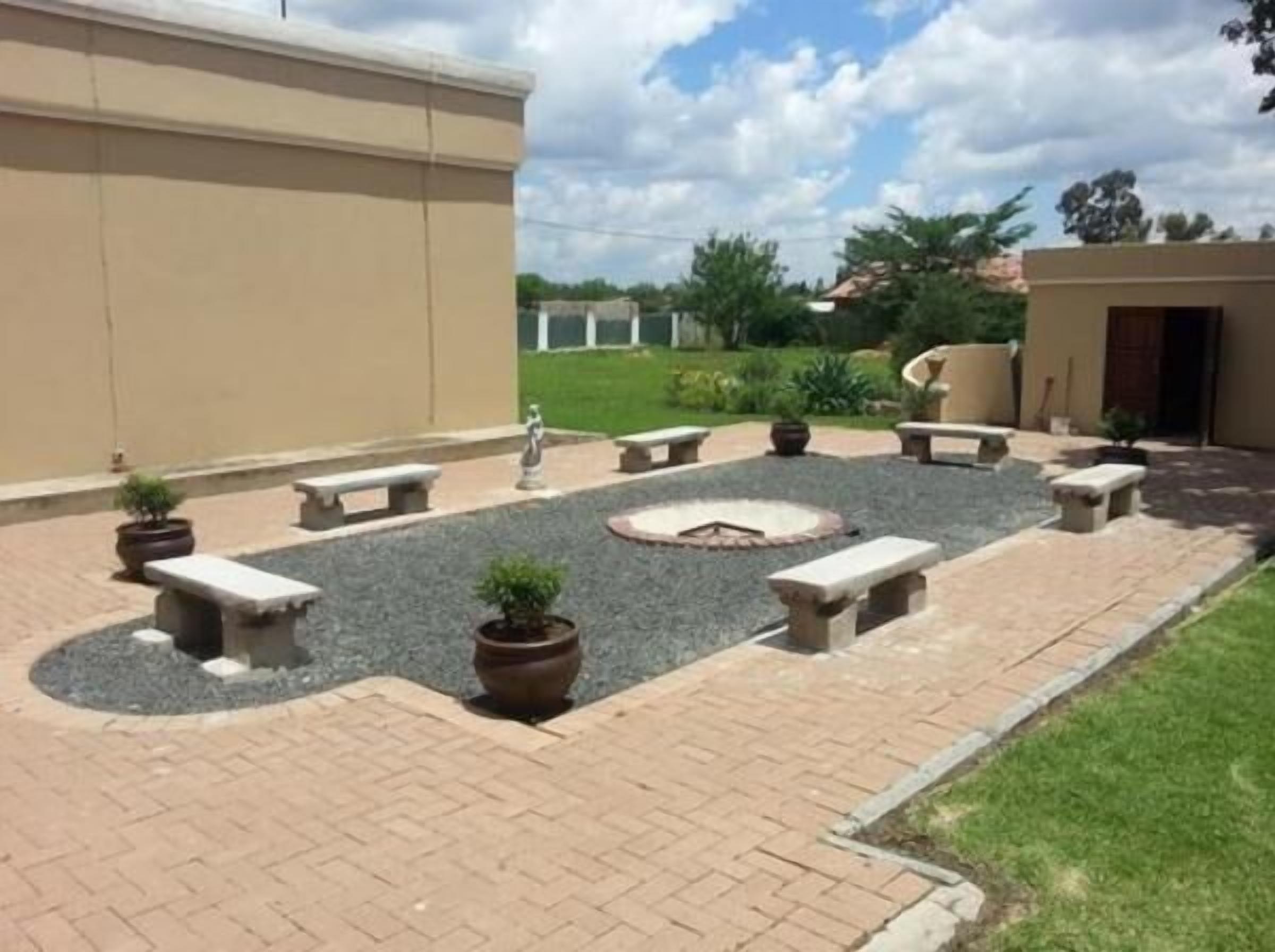 A courtyard with stone benches, a circular fire pit, and potted plants.