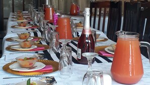 A long dining table set for a meal with various dishes, glasses, and a large pitcher of juice. - The Guest House (Lekwa)