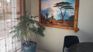 A room with a large painting of a landscape, a potted plant, and a chair. - The Guest House (Lekwa)