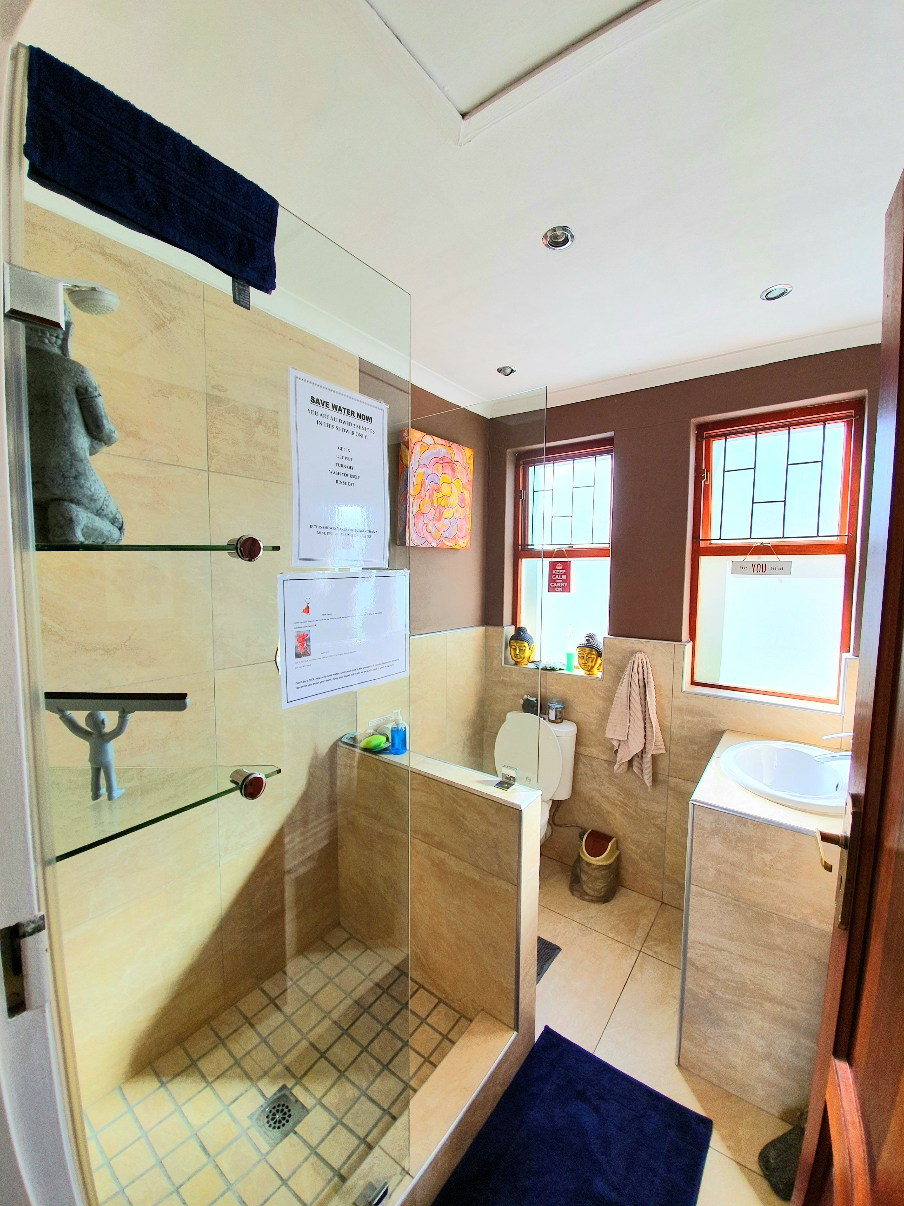 A modern bathroom with a glass shower enclosure, a toilet, a sink, and a window with a view.