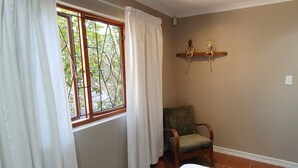 A room with a window, a chair, and a wall-mounted shelf. - Happy Home Imhoffs Gift (Cape Town)