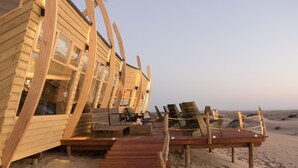 Una casa sulla spiaggia in legno con veranda e poltrona relax.