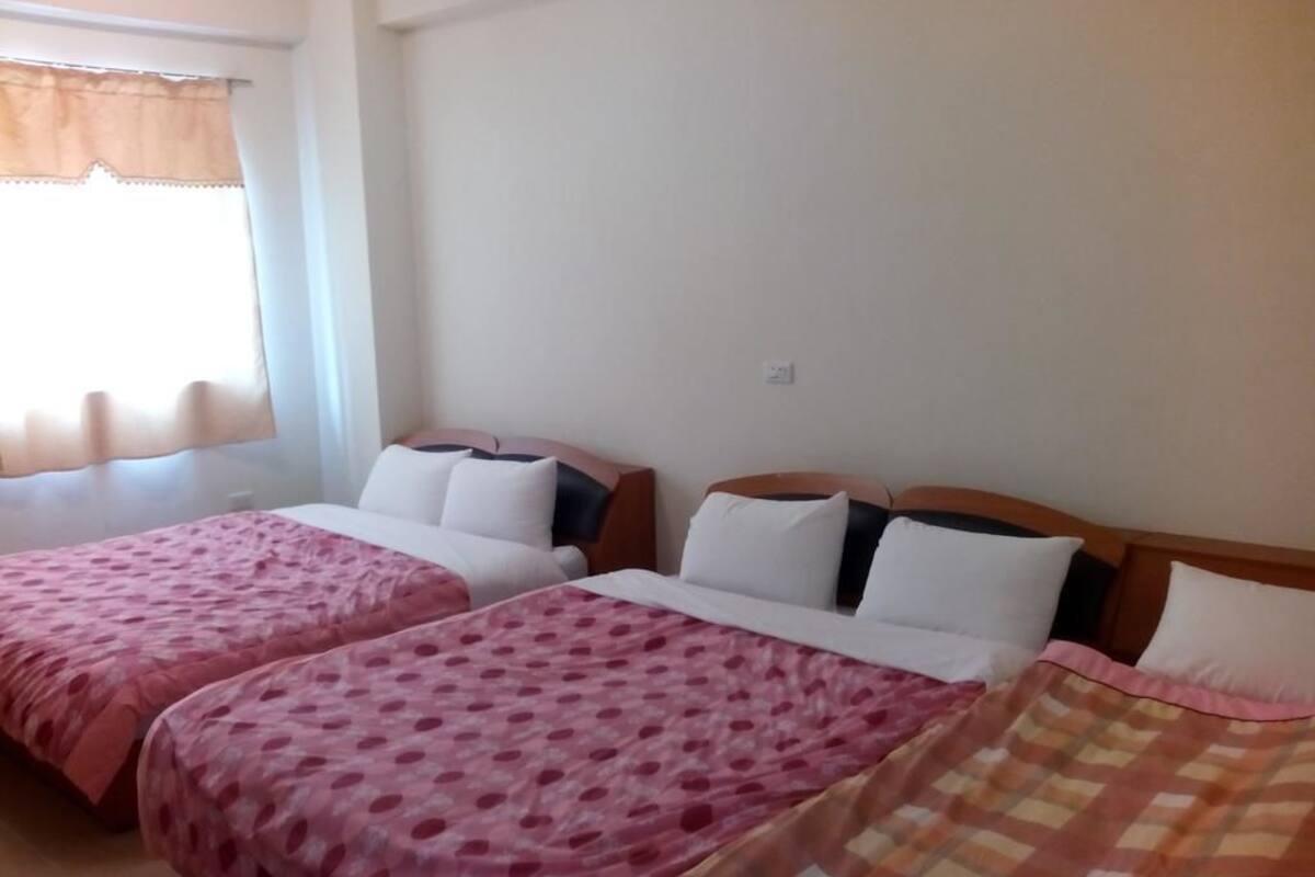 A hotel room with two beds, each with a patterned bedspread, a wooden headboard, and white pillows.