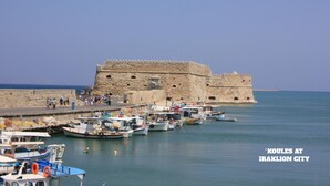A fortified structure with a moat, boats docked in the water, and a clear sky. - Popis sea view apartments ''Studio Dim'' (Mades, Gazi, Iraklion)