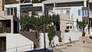A residential building with multiple balconies, some with railings, and a few potted plants. - Popis sea view apartments ''Studio Dim'' (Mades, Gazi, Iraklion)