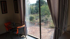 A room with a large sliding glass door leading to an outdoor area with a brick patio and greenery. - 24 Bush House (Bela-Bela)