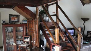 A staircase with wooden railings and a chair with a cowhide seat. - 24 Bush House (Bela-Bela)