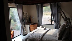 A bedroom with a bed, a desk, and a chair. There are curtains on the windows, and a fan is on the desk. - 24 Bush House (Bela-Bela)
