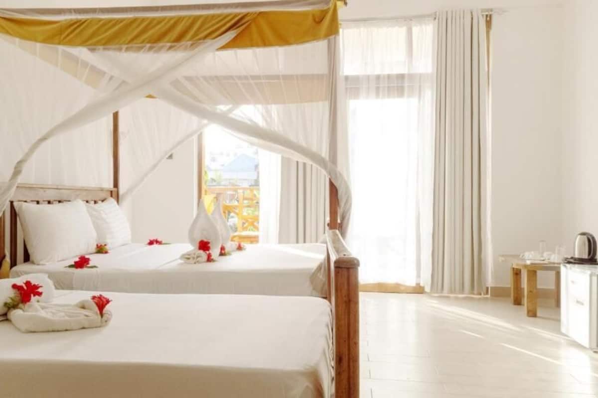 Ein Hotelzimmer mit zwei Betten, einem Himmelbett, einem kleinen Tisch und einem Schrank.