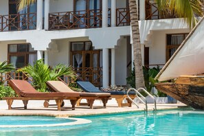 A pool area with lounge chairs and a wooden boat. - Nungwi Garden Boutique Hotel (Nungwi)