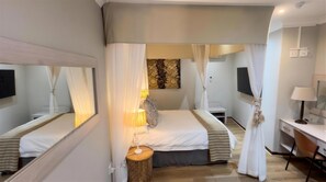 A hotel room with a bed, bedside table, lamp, and a desk with a chair. - Constantia Hotel and Conference Centre (Midrand)