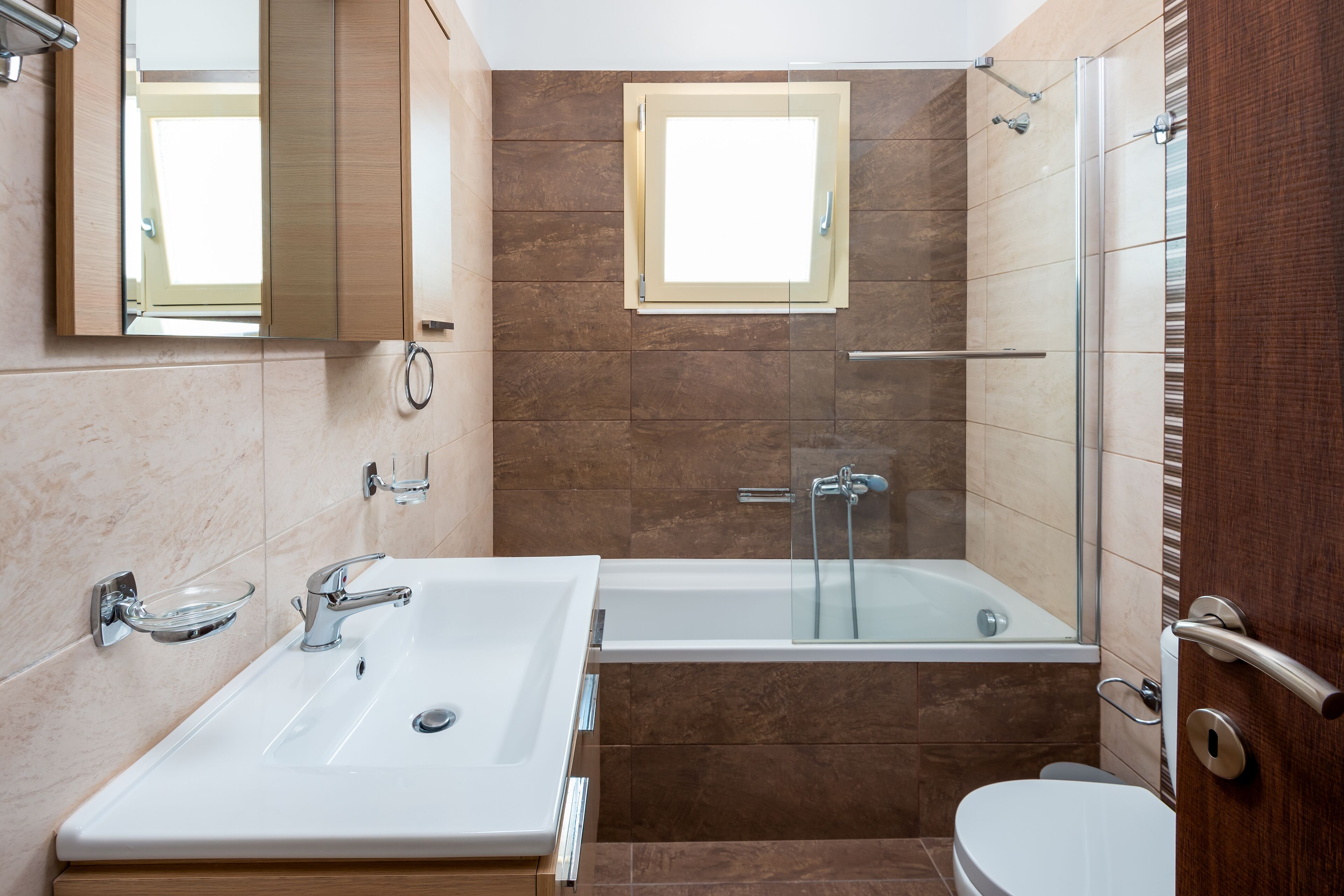 A modern bathroom with a double sink, a bathtub, and a glass-enclosed shower.