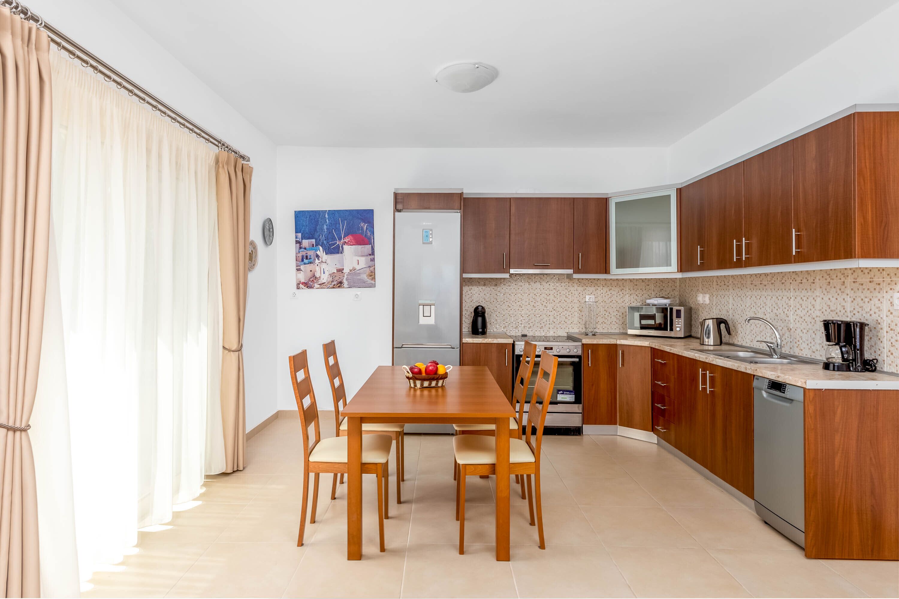 Eine moderne Küche mit Holzschränken, einem Esstisch mit Stühlen und einem Kühlschrank.
