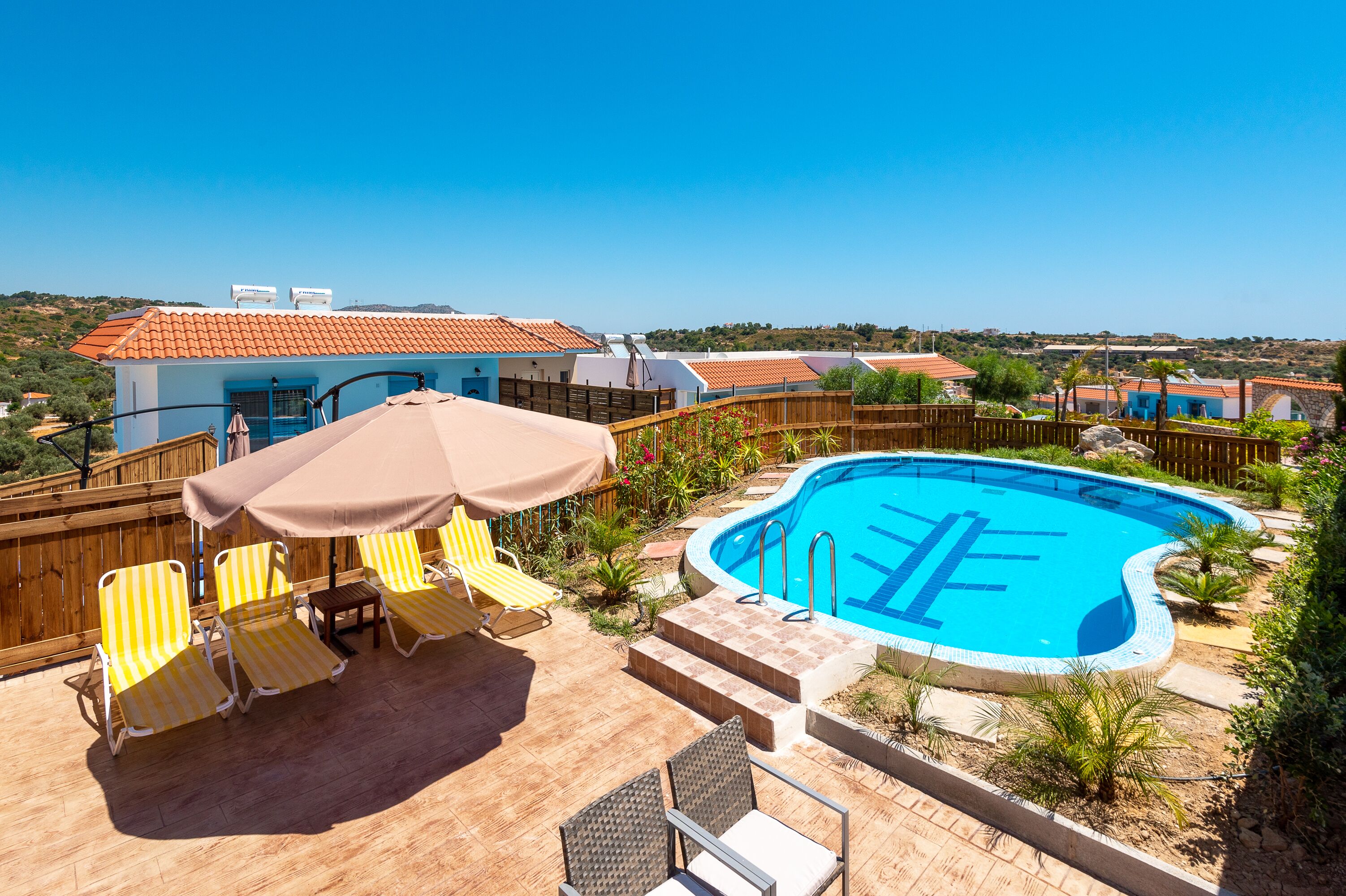 Un patio trasero con piscina, tumbonas y cerca de madera.