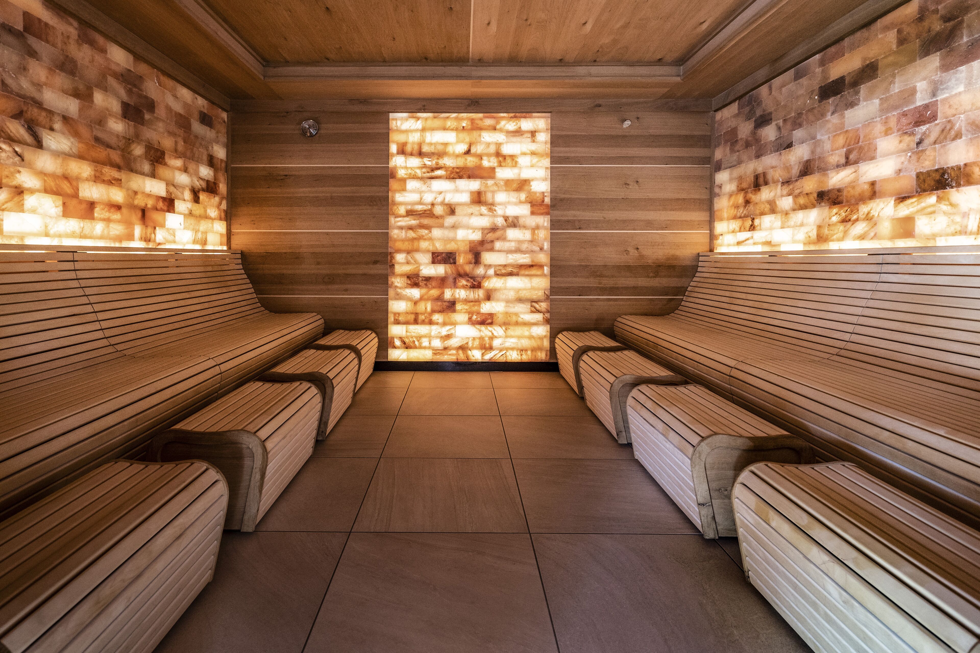 Una sala de sauna con bancos de madera y una pared de mosaicos.