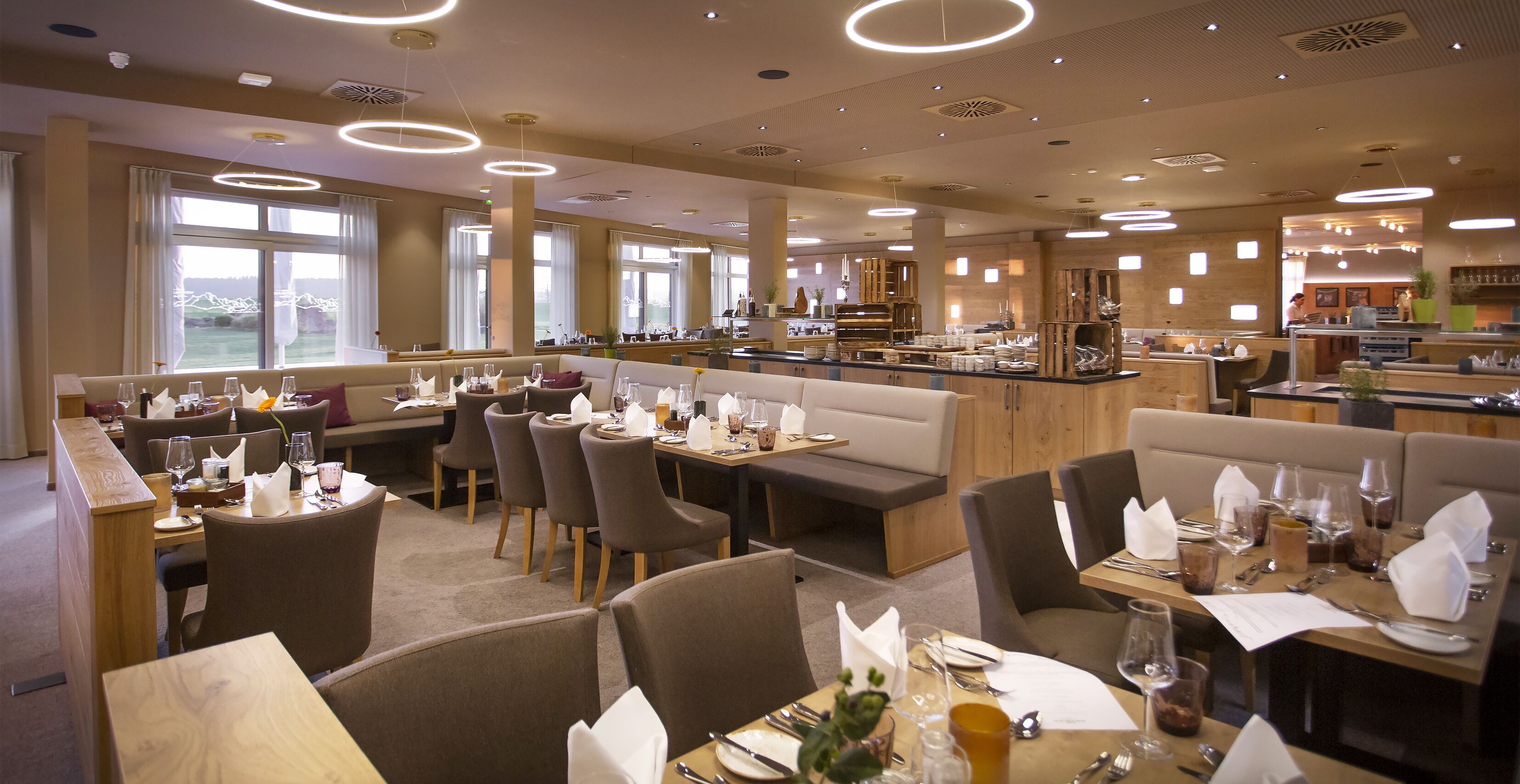 A modern restaurant with multiple dining areas, including booths and tables, and a bar area.