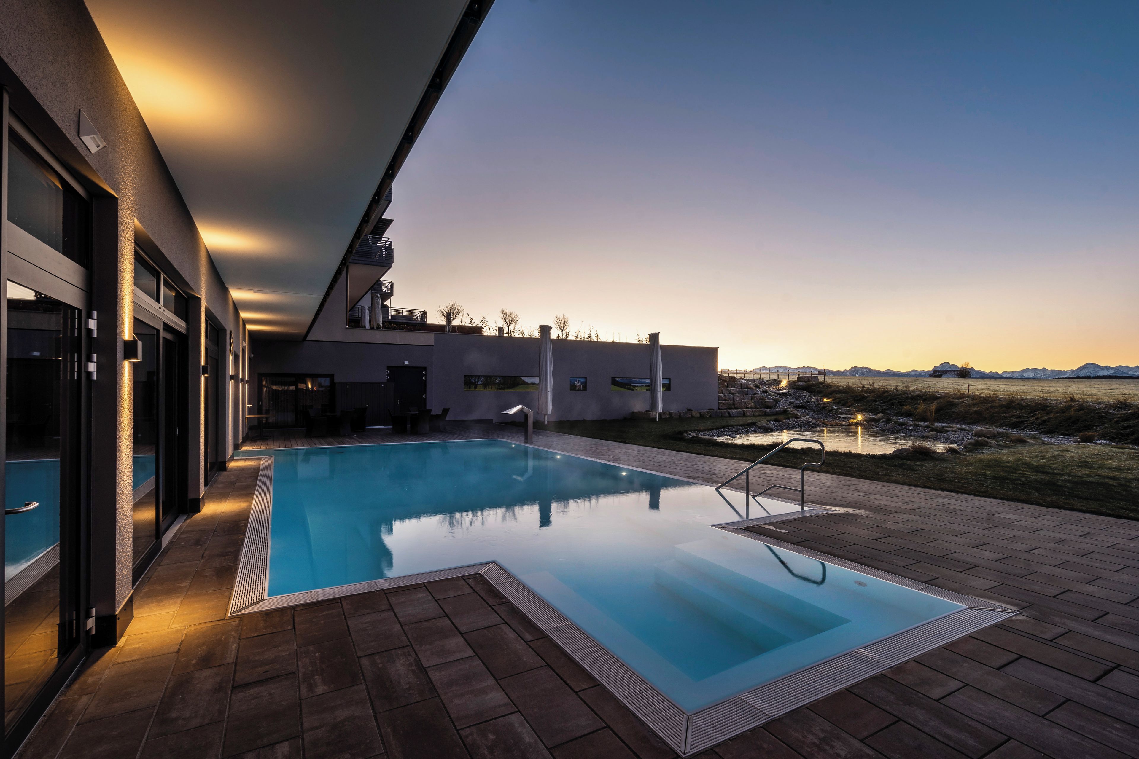 Ein moderner Pool im Freien mit freiem Blick auf die umliegende Landschaft und Berge.