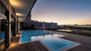 A modern outdoor swimming pool with a clear view of the surrounding landscape and mountains.
