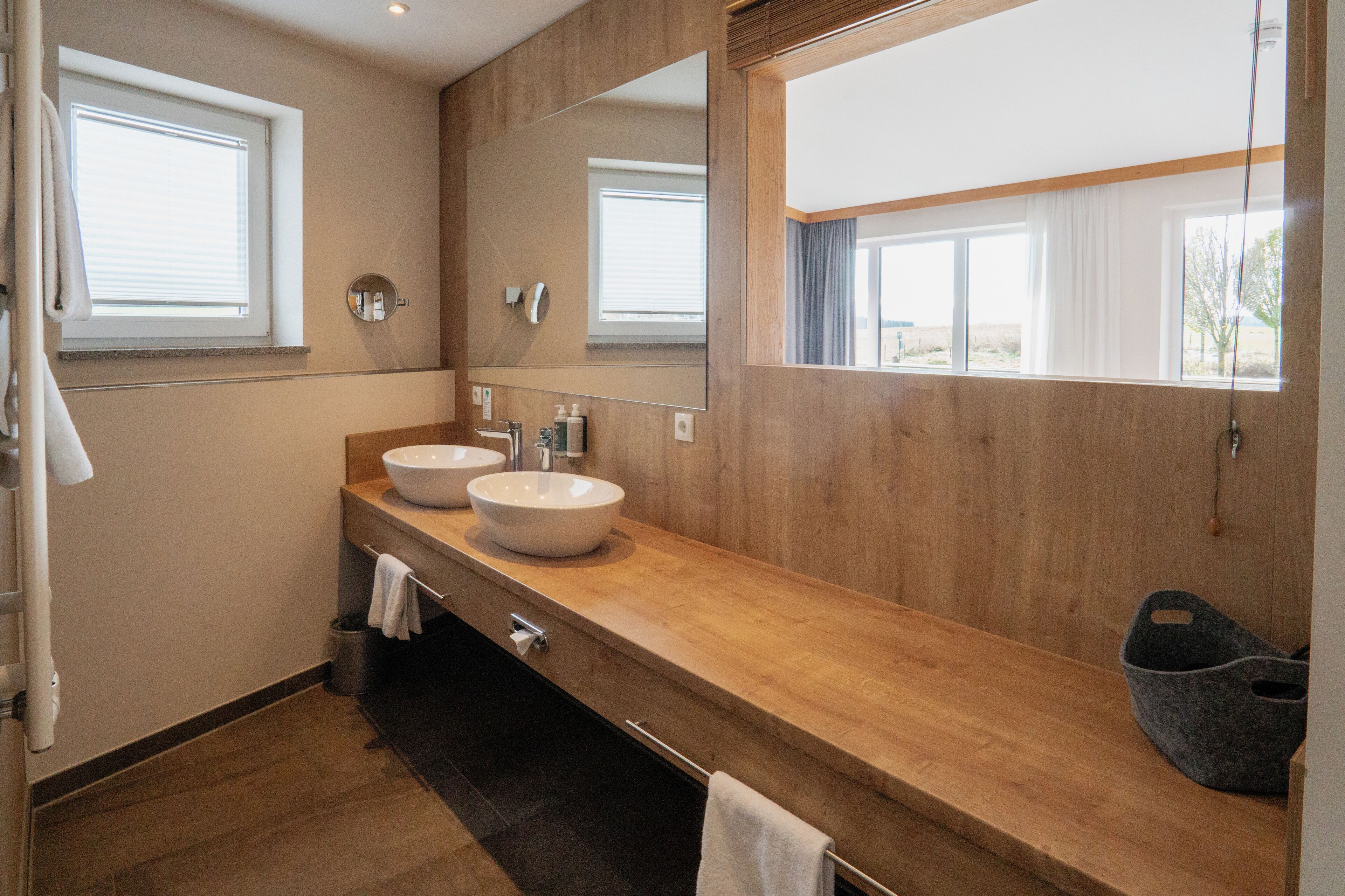 Une salle de bain moderne avec deux lavabos, un grand miroir et une fenêtre.