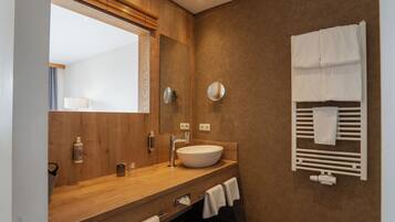 Une salle de bain moderne avec un meuble-lavabo en bois, un grand miroir, un porte-serviettes intégré et un lavabo blanc.