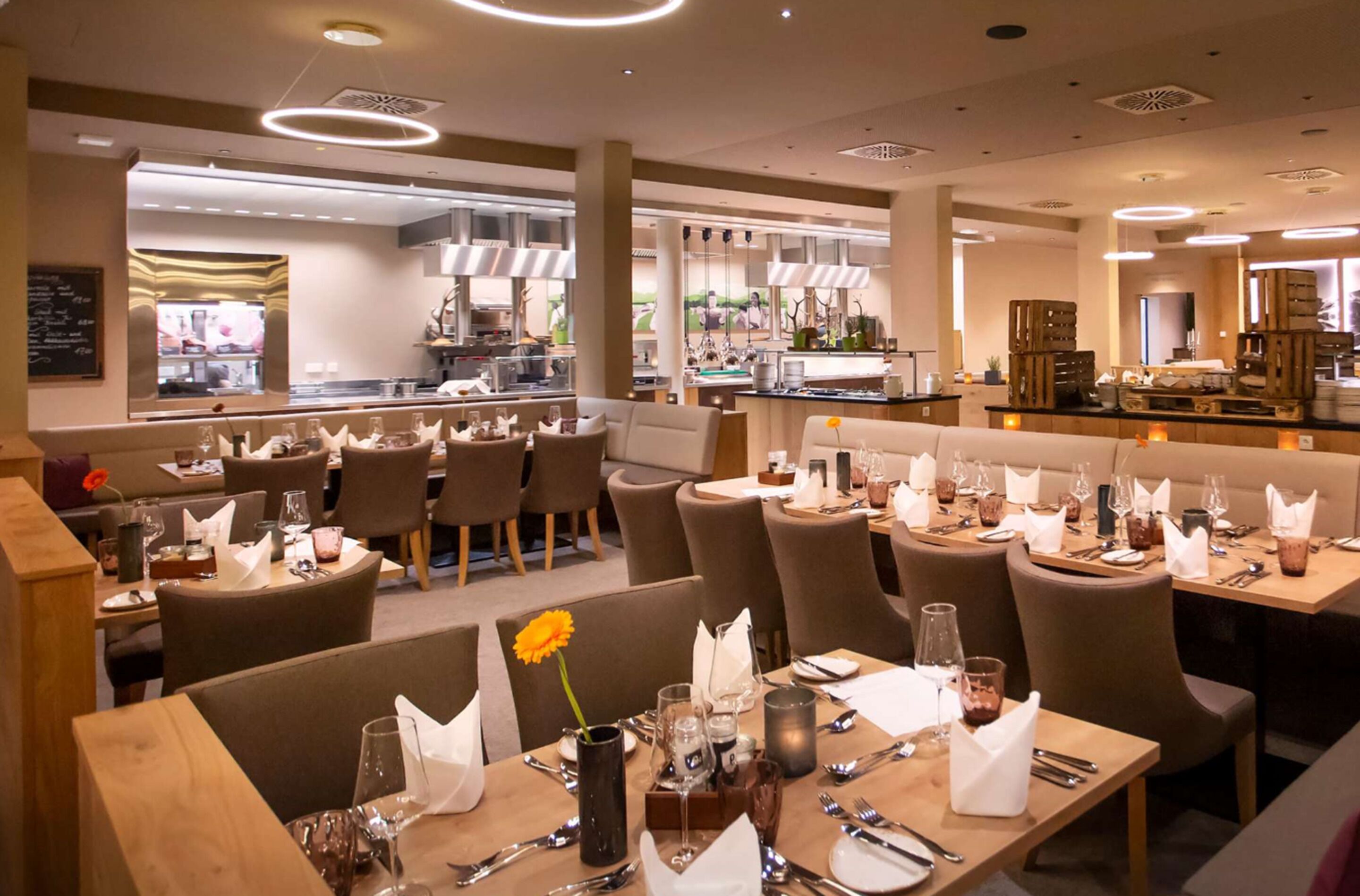 Un restaurante con varias mesas dispuestas para comensales, con una decoración interior moderna en tonos neutros e iluminación ambiental.