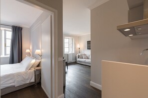 Una habitación de hotel moderna con cama, mesita de noche, lámpara y vistas al área de estar.