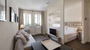Une chambre d’hôtel moderne équipée d’un canapé, d’une télévision, d’un lit et d’une petite table.