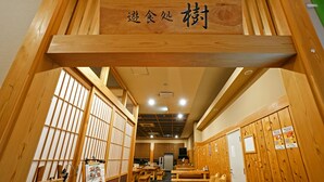 A traditional Japanese restaurant interior with wooden furniture, tatami mats, and a sign indicating a dining area.
