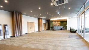A spacious lobby with a reception desk, wooden paneling, and a large window providing natural light.