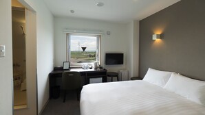 A hotel room with a bed, desk, chair, and a TV mounted on the wall.