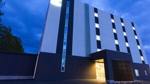A modern building with a flat roof, a vertical light strip, and a large entrance.