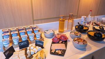 A buffet with various cheeses, meats, and condiments.