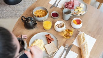 Une table de petit-déjeuner avec des assiettes remplies de nourriture, une théière et une tasse de thé.